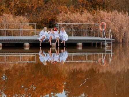 Frauen sitzen am Schwimmteich im Herbst