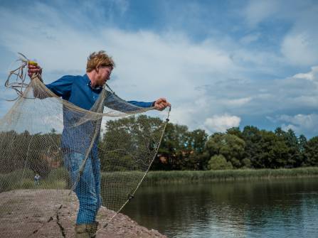 Fischer mit Fischernetz am Weiher
