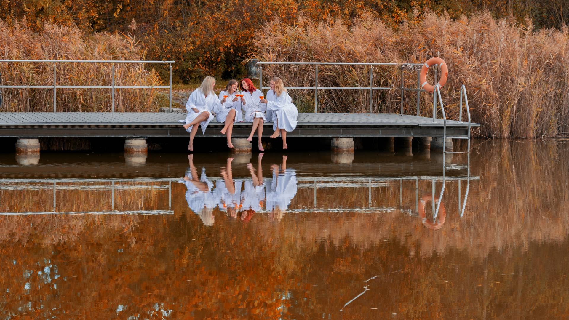 Frauen sitzen am Schwimmteich im Herbst
