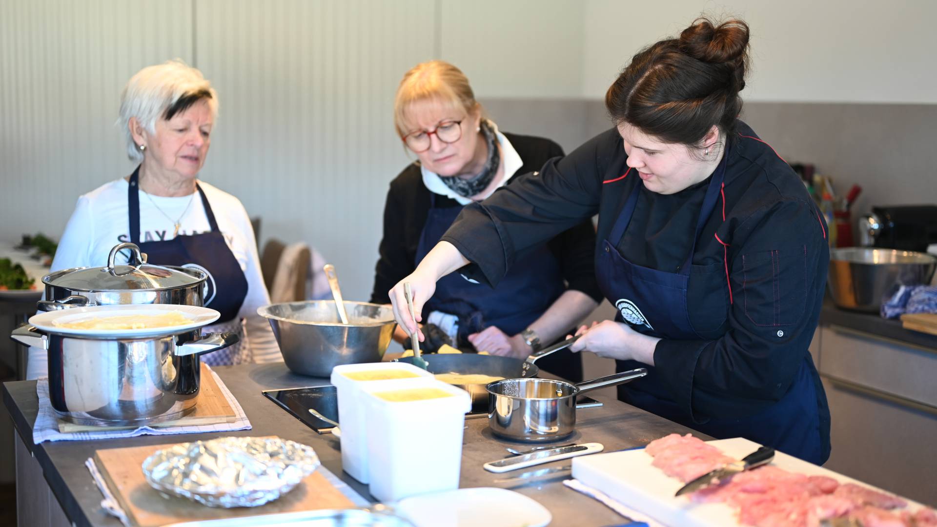 Köchin zeigt beim Kochkurz, wie man Pfannkuchen macht