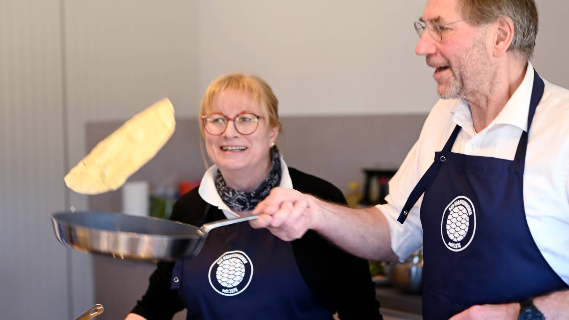 Mann wendet Pfannkuchen in der Luft mit der Pfanne